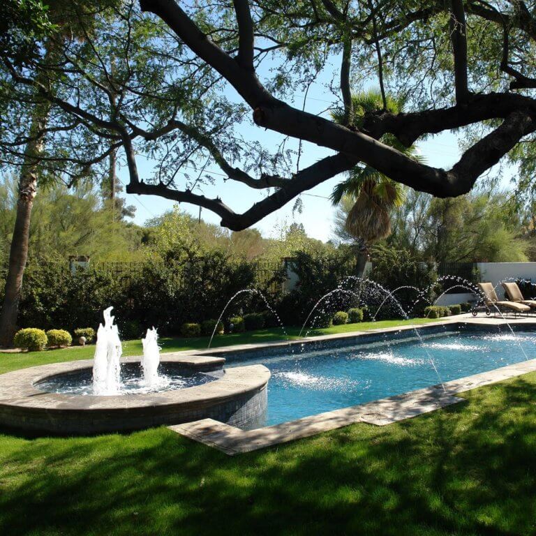 A well-maintained yard with a large pool and fountain