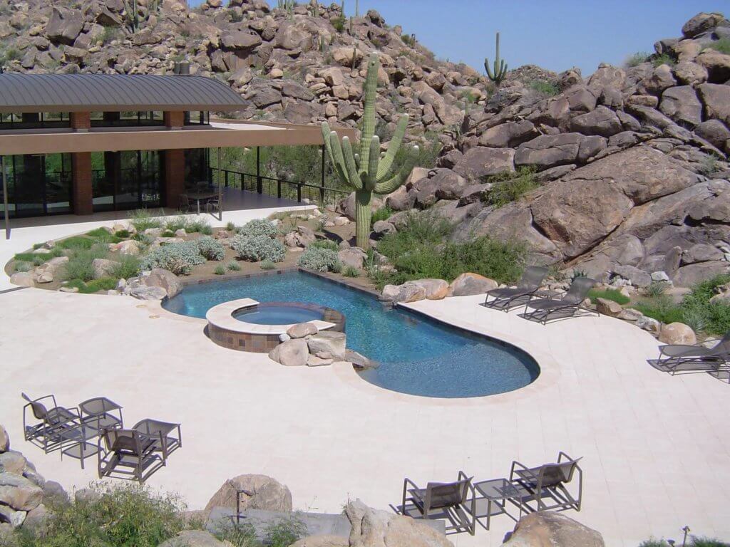Outdoor patio area with a large custom pool and landscaping