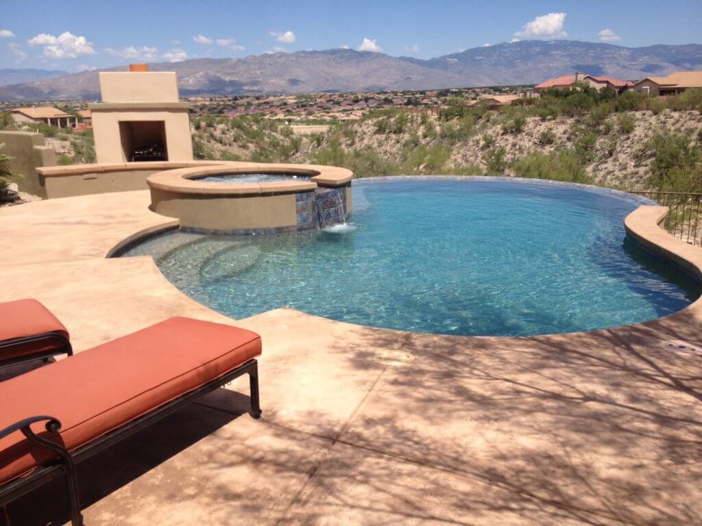 Round hot tub with a waterfall into an infinity pool with a view of the Arizona mountains