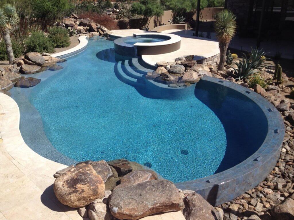 Custom hot tub and pool with a curved waterfall edge