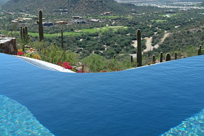 A large curved pool with an infinity edge overlooking Arizona hills